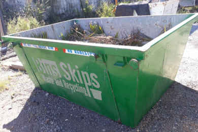 A mini skip containing lawn clippings and other green waste from a clean up process